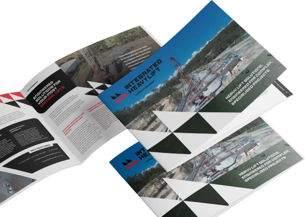 Three brochures for Integrated Heavylift are displayed on a white surface. The covers show an aerial view of a construction site with cranes, while the open brochure reveals text, images, and geometric design elements.